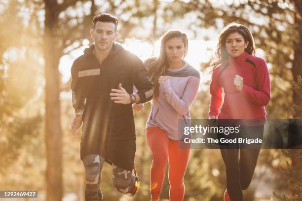 dedicated male and female athletes running in forest during sports training - langstreckenlauf stock-fotos und bilder