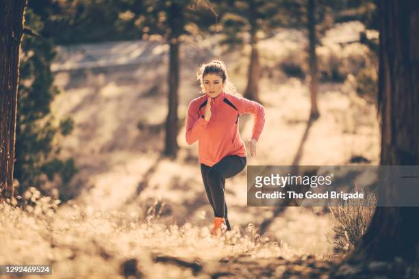 dedicated female athlete running in forest during sports training - uphill stockfoto's en -beelden