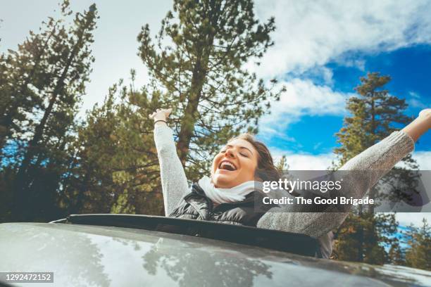 woman leaning out sun roof of car with hair blowing in wind - sunroof stock pictures, royalty-free photos & images