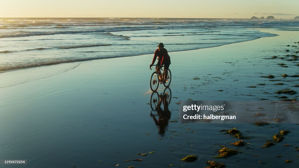 Man Cycling Along Shoreline on Oregon Beach - Drone Shot