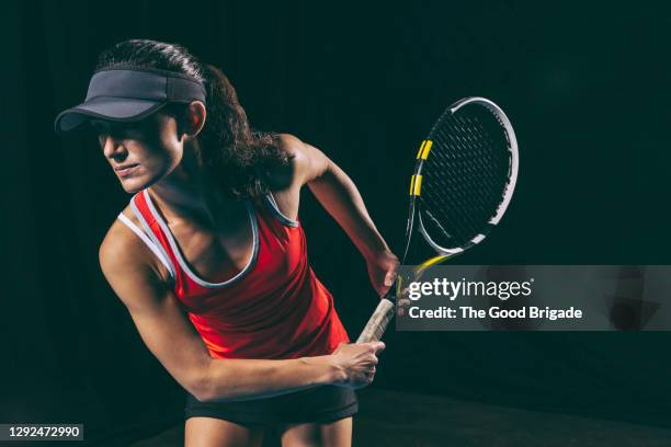 confident female tennis player practicing against black background - tennis game stock pictures, royalty-free photos & images