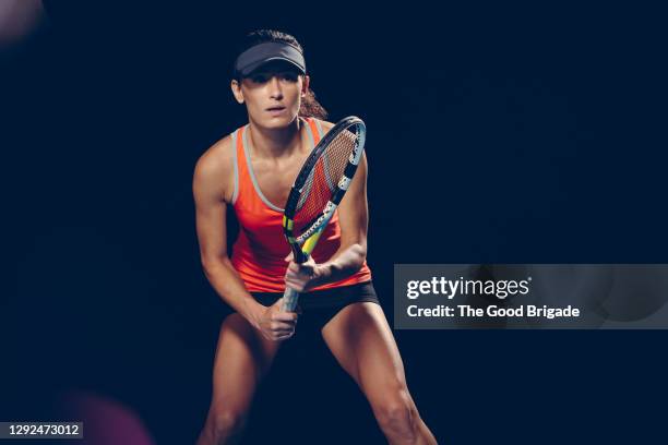 confident woman practicing tennis against black background - tennis player stock pictures, royalty-free photos & images