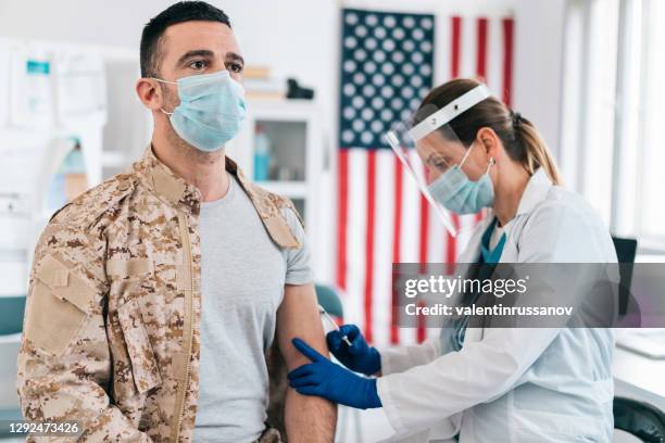 doctor wearing protective work wear injecting covid-19 vaccine to soldier - 37 military hospital stock pictures, royalty-free photos & images