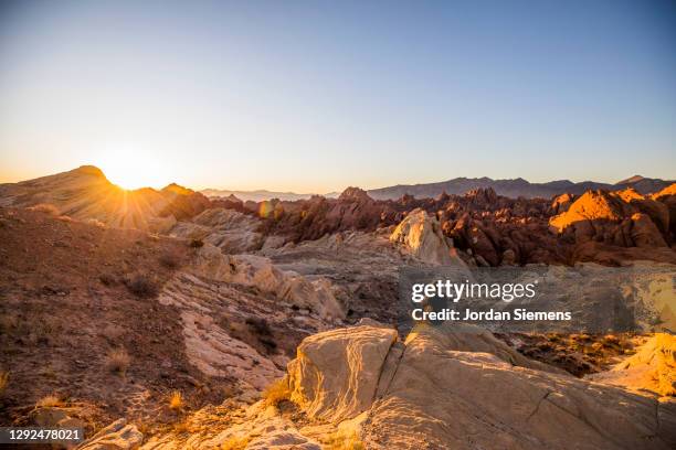 a man sitting on a rock watching the sunrise in the desert. - rock terrain stockfoto's en -beelden