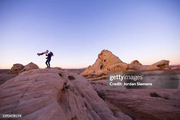 a woman swinging her son around while hiking in the desert. - nevada landscape stock pictures, royalty-free photos & images