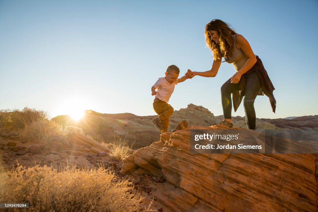 A pregnant mother and her son hiking in the desert.