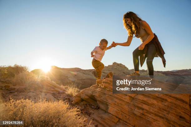 a pregnant mother and her son hiking in the desert. - mid adult stock-fotos und bilder