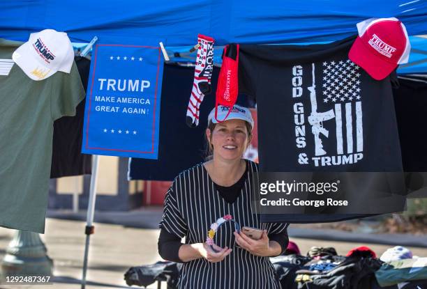 Woman sells Donald Trump hats and shirts while listening to speakers decry a stolen election and demand the state open all businesses during an...