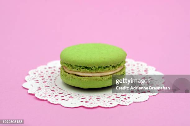 one pistachio macaroon on a doily - doily stock pictures, royalty-free photos & images