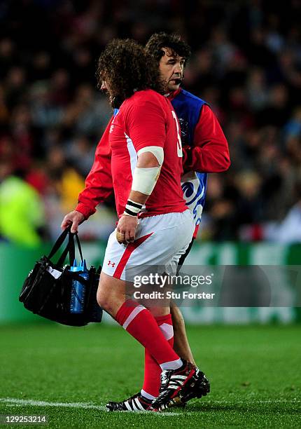 Injured prop Adam Jones of Wales is helped off the pitch by Physio Mark Davies during semi final one of the 2011 IRB Rugby World Cup between Wales...