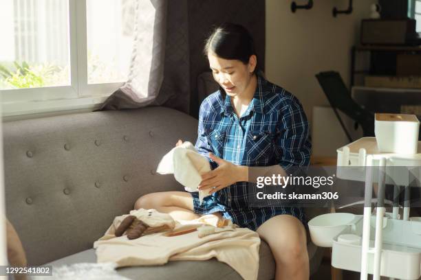 asian female young adult pregnant woman smiling and very happy preparing cloth for childbirth - prenatal class stock-fotos und bilder