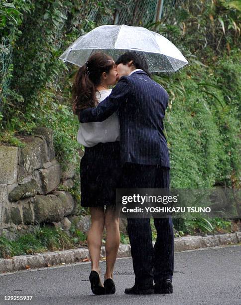 Couple kiss during heavy rain along a street in Yokohama, suburban Tokyo on October 15, 2011. Heavy rains hit the Pacific coastal areas in Japan...