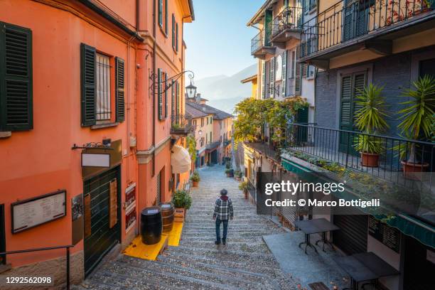 one man walking in a tiny alley in bellagio, lake como, italy - bellagio stock-fotos und bilder