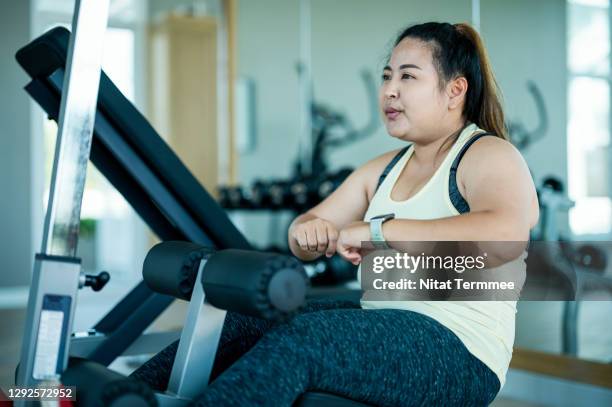 overweight asian woman doing sit ups by sit-up machine at gym. - fat asian woman stock-fotos und bilder