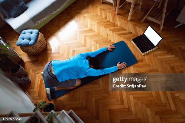 young man in child's pose at home following online yoga class - child yoga elevated view stock pictures, royalty-free photos & images