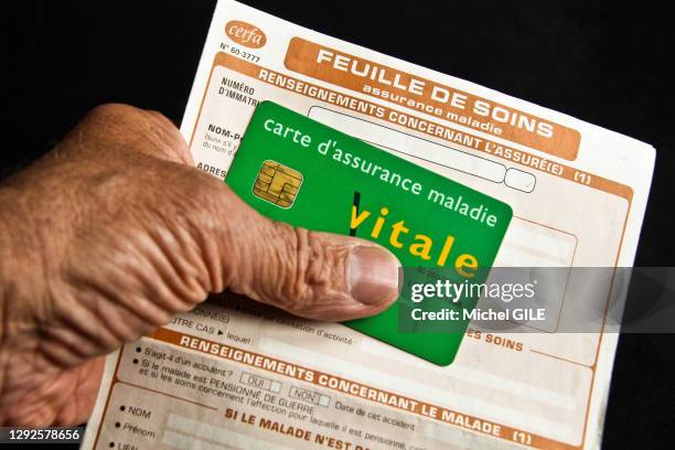 Main tenant une feuille de soins de l'assurance maladie et une carte vitale, 5 juin 2020, France.