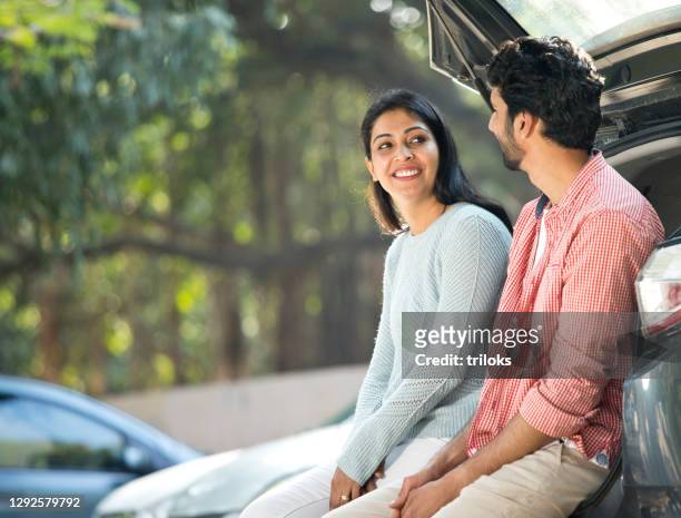 couple looking at each other in car trunk - indian ethnicity man car stock pictures, royalty-free photos & images