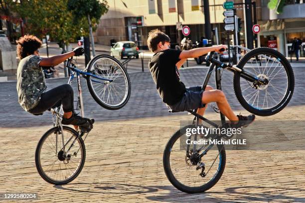 Deux adolescents s'amusant à faire du vélo sur une seule roue, place des Jacobins, au Mans, France, le 26 octobre 2019.
