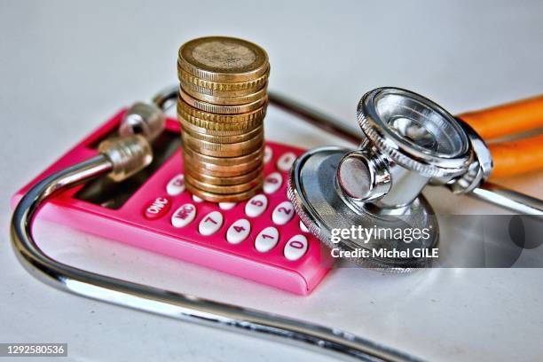 Santé et pouvoir d'achat, pile de pièces de monnaie en Euros sur une calculatrice rose et stéthoscope, 17 février 2019, France.