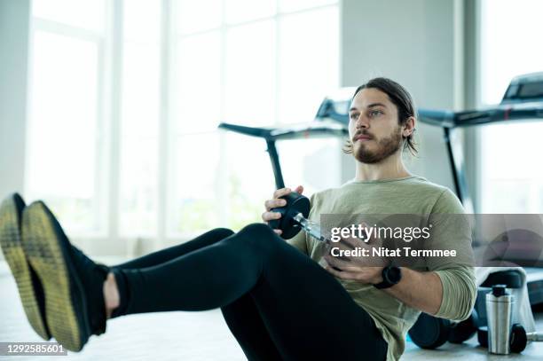 men exercising sit-ups with heavy dumbbell in a health club. weights lifting, and cross training workout. - weight training 個照片及圖片檔