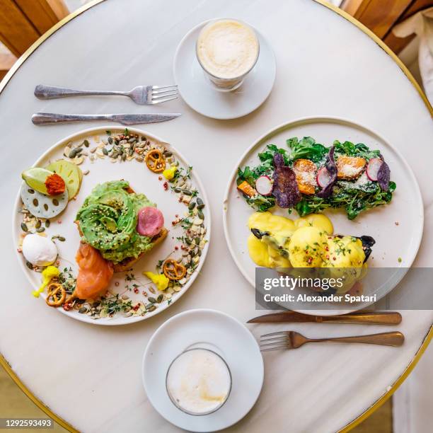 breakfast for two persons with avocado toast and eggs benedict on waffle, directly above view - cafe symmetry stock pictures, royalty-free photos & images