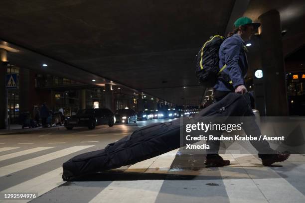traveler carrying skis to airport at night - ski pants stock-fotos und bilder
