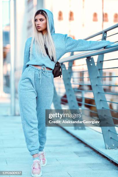 hermosa hembra en chándal caminando sobre el puente y sosteniendo la barandilla - tracksuit fotografías e imágenes de stock