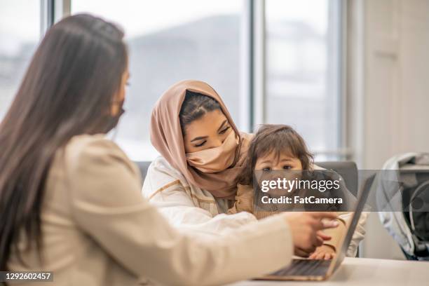 muslim family healthy baby check up at family doctor - refugee health stock pictures, royalty-free photos & images