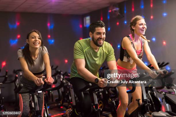 stationary exercise cycling class with disco ambient lights, happy people training together. - cycling gym stock pictures, royalty-free photos & images