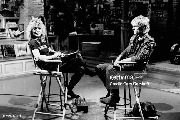 View of American VJ Nina Blackwood and Canadian Rock musician Bryan Adams as they sit in director's chairs during an interview at MTV Studios, New...