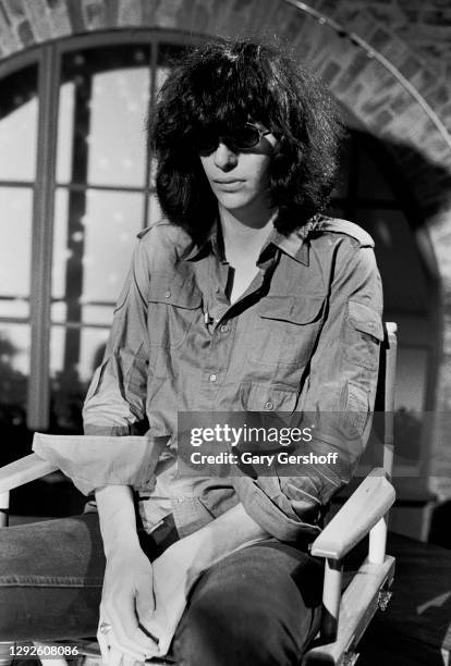View of American Punk Rock musician Joey Ramone as he sits in a director's chair during an interview at MTV Studios, New York, New York, April 1,...