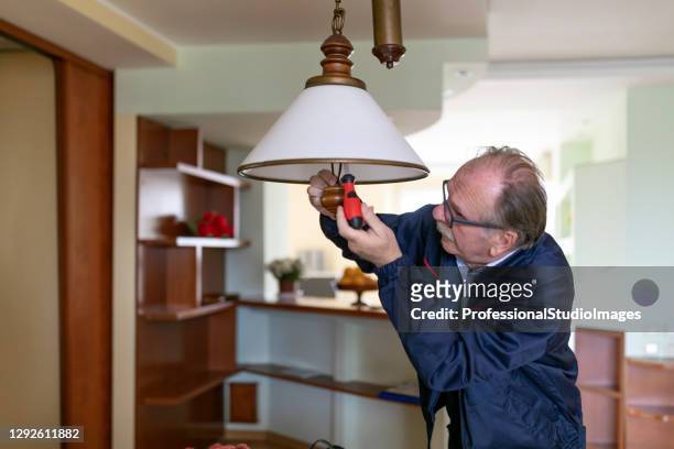 ein leitender elektriker repariert eine elektrische lampe mit seinen werkzeugen. - senior blaumann stock-fotos und bilder