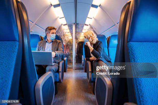 corona practices for a commuter train traveller business couple - commuter mask stock pictures, royalty-free photos & images