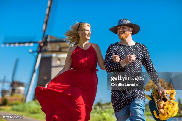 en holländsk kvinna och crossdress man på en väderkvarn - medelålderskris bildbanksfoton och bilder