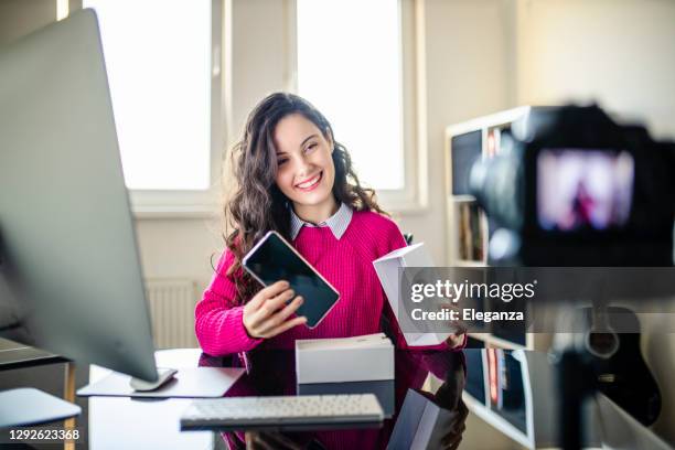 influencer della tecnologia dei social media femminile che registra video di unboxing a casa - recent foto e immagini stock