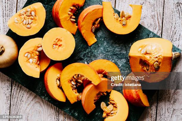 sliced pumpkin on green stone chopping board - squash seeds stock-fotos und bilder