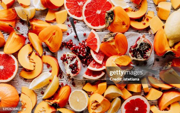 various sliced fruits and pumpkins on wooden table - winter vegetables foto e immagini stock