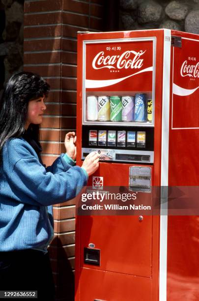 General view of a South Korean woman putting in her money to buy something from the Coca-Cola vending machine in the Hawan District circa April, 1987...