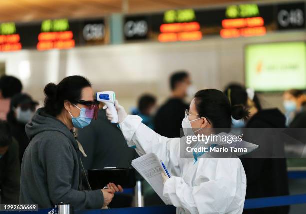 Traveler receives a a temperature check before checking in for a China Airlines flight at the Tom Bradley International Terminal at Los Angeles...