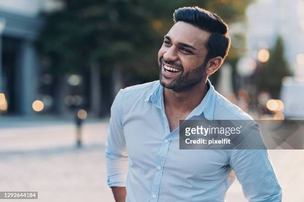 lächelnder junger mann im freien in der stadt - looking away stock-fotos und bilder