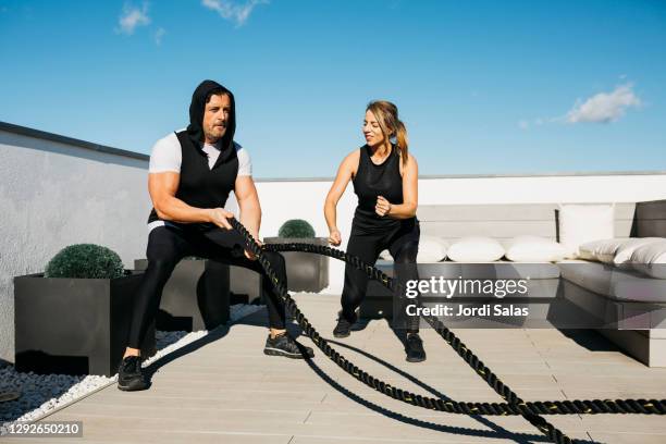 man working out with battle ropes - female battle ropes stock pictures, royalty-free photos & images