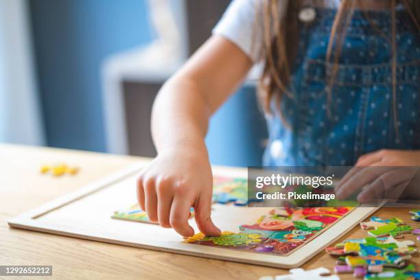 meisje dat met raadsels thuis speelt - puzzel stockfoto's en -beelden