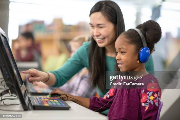 asian teacher helping student in library with computer - kids at community center stock pictures, royalty-free photos & images