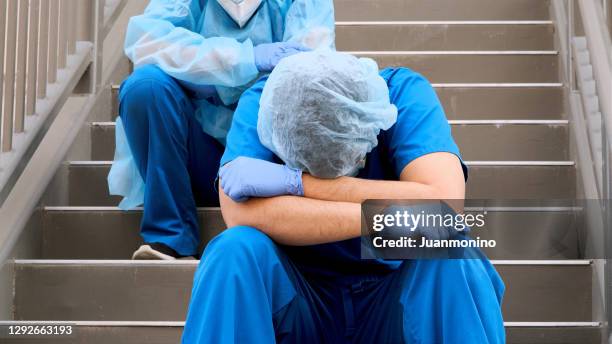 serious, overworked, health care workers wearing protective face masks and very sad - coronavirus nurse stock pictures, royalty-free photos & images