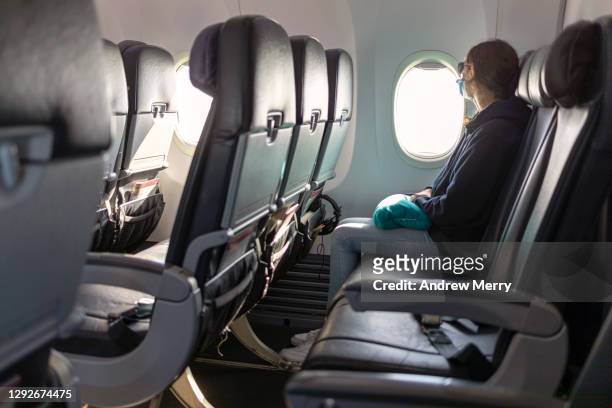 air travel, passenger looking out airplane window, empty seats, covid-19 - 飛行機の座席 ストックフォトと画像