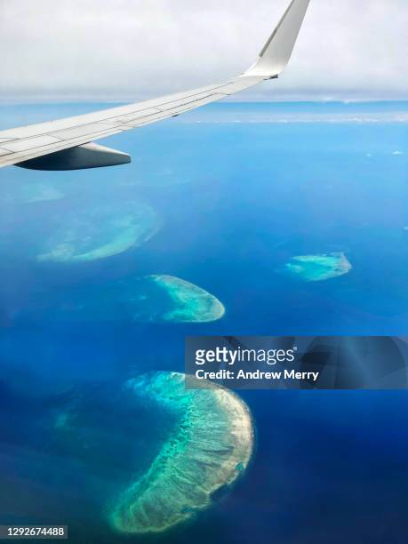 great barrier reef and coral sea, airplane window view with aircraft wing - airport aerial view photos et images de collection
