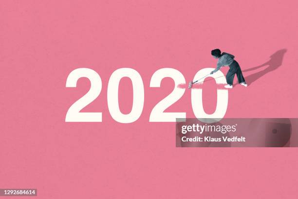 young woman painting over 2020 with pink roller - 2020 stock-fotos und bilder