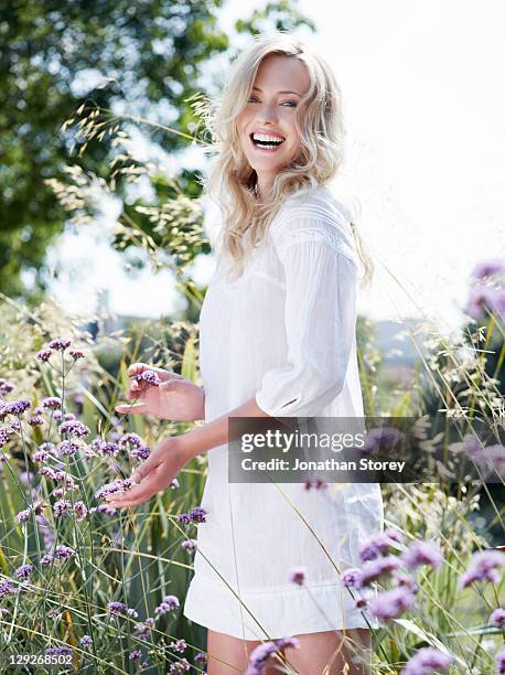 full body shot of female standing in wild flowers - beautiful woman laughing stock pictures, royalty-free photos & images