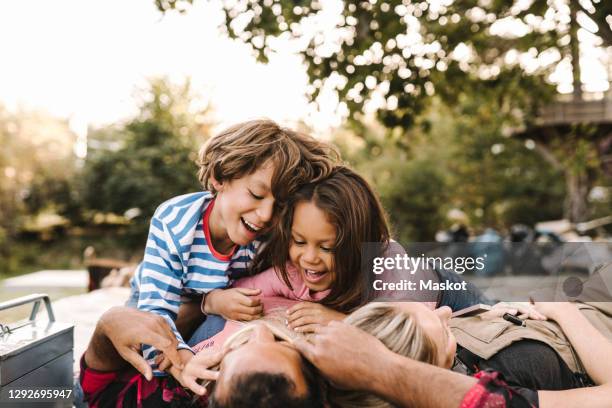 smiling children enjoying with parents while lying in yard after renovating during summer - two kids playing with hose stock pictures, royalty-free photos & images