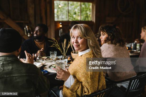 portrait of smiling woman enjoying with drinking glass by friends during social gathering - holiday house stock pictures, royalty-free photos & images
